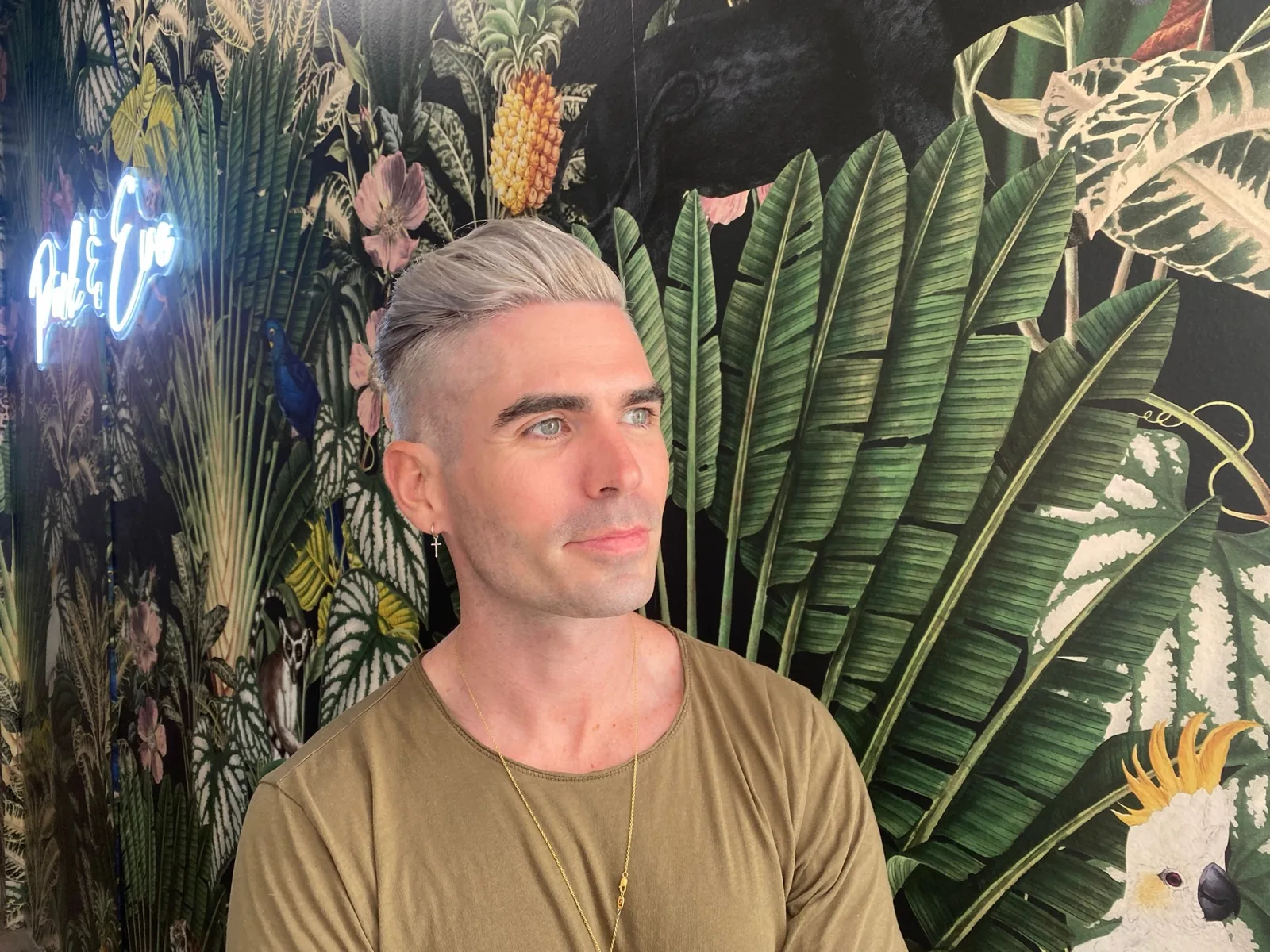 Men's platinum blonde color and cut against the Park & Eve neon wall in Downtown Los Angeles